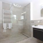 Badezimmer mit Dusche, Handtuchhalter und Waschbecken.