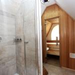 Dusche mit Glaswand und Holzsauna mit Sitzbank