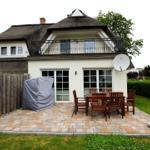 Haus mit Dachterrasse, Terrasse mit Tisch und Stühlen, Satellitenschüssel und Garten.