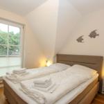Schlafzimmer mit Doppelbett, Fenster und Wanddekoration.