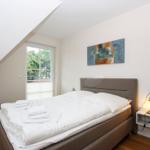 Schlafzimmer mit Bett, Fenster und Wandbild. Nachttisch mit Laterne.