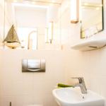 Badezimmer mit Waschbecken, Spiegel und Segelboot-Dekoration.