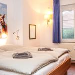 Schlafzimmer mit Bett, Wandbild von Kühen, Fenster und Wandleuchte.