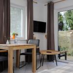 Essbereich mit Tisch, Stühlen und Fernseher. Durchgang zur Terrasse mit Gartenblick.