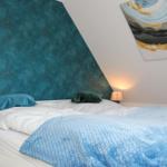 Schlafzimmer mit Bett, blauer Wand und Wandbild.