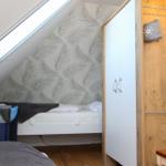 Schlafzimmer mit Dachschrägen, Babybett und Kleiderschrank.