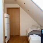 Schlafzimmer mit Dachschrägen, Bett, Kinderbett und Schrank. Dachfenster sorgt für Tageslicht.