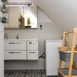 Waschraum mit Spiegelschrank, Waschmaschine und Badezimmermöbel.