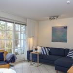 Wohnzimmer mit Sofa, Sessel und Fenster zur Terrasse.