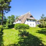 Haus mit Strohdach und weißer Fassade im Grünen