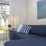 Ein Wohnzimmer mit blauem Sofa, Kissen und einer Glastür zum Garten.