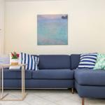 Ein blauer Sofa mit Kissen und einem Tisch vor einer Wand mit Bild.
