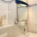 Badezimmer mit Spiegel, Waschbecken und Heizkörper an der Wand.