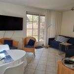 Wohnzimmer mit Sofa, Esstisch und TV. Fenster zur Außenseite.