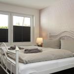Schlafzimmer mit Bett, Fenster und Tapete an der Wand.
