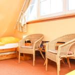Zimmer mit Bett, zwei Stühlen und Fenster.
