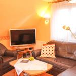 Wohnzimmer mit Sofa, Sessel, Fernseher und Tisch.
