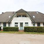 Ein zweistöckiges Haus mit Balkon, grünen Fensterrahmen und Schiebetüren.