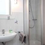 Badezimmer mit Waschbecken, Spiegel und Dusche mit Glaswand.