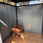 Holzschubkarre mit roten Rädern in einem Metallcontainer mit OSB-Boden.