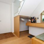 Schlafzimmer mit Dachschräge, Kleiderschrank und Schreibtisch mit Spiegel.
