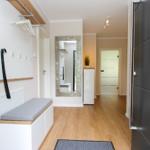 Eingangsbereich mit Garderobe, Sitzbank und Spiegel. Holzboden und moderne Einrichtung.