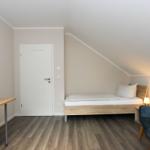 Zimmer mit Bett, Fernseher und Sessel unter Dachschrägen