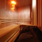 Sauna mit Holzbank, Wärmegeber und Thermometer an der Wand.