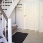 Hausflur mit Treppe, Kleiderständer und zwei Türen.