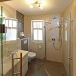 Badezimmer mit Dusche, WC und Waschbecken. Fenster sorgt für Tageslicht.