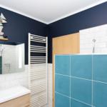 Badezimmer mit blauen Wänden, weißer Fliesenwand und Holzwaschbecken.