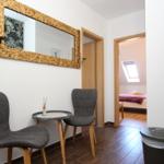 Eingangsbereich mit zwei Stühlen und Tisch. Im Hintergrund ist ein Schlafzimmer mit Dachfenster sichtbar.