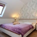 Schlafzimmer mit Dachfenster, Bett mit Laken und Nachttische.