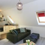 Wohn- und Küchenbereich mit grünem Sofa, Dachfenster und Pendelleuchte.