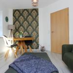 Wohnzimmer mit Sofa, Esstisch und dekorativer Wandtapete.