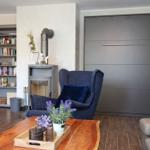 Wohnzimmer mit Sitzgelegenheiten, Kamin und Bücherregal. Holztisch mit Pflanzen.