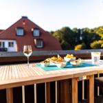 Tisch auf Terrasse mit Getränken und Snacks, Blick auf Haus und Bäume.