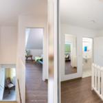 Haus mit Treppenhaus, Schlafzimmer und Bad. Holzfußboden und weiße Wände.