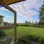 Durch das Fenster blickt man auf einen grünen Garten und einen See.