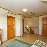 Wohnbereich mit Bücherregal, Holztreppe und mehreren Türen.