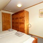 Schlafzimmer mit Holzbett, Kleiderschrank und Tür. Auf Bett liegen Handtücher.