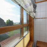 Badezimmer mit Holzfenster, Blick auf Dach und Grünfläche