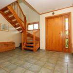 Eingangsbereich mit Holztreppe, Tür und Holzbank. Fliesenboden und Wandgestaltung.