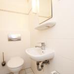Badezimmer mit Toilette, Waschbecken und Spiegel an der Wand.