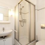 Badezimmer mit Dusche, Waschbecken und Toilette.