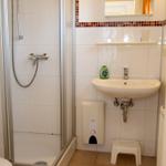 Badezimmer mit Dusche, Waschbecken und Spiegel.