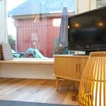 Wohnzimmer mit TV, Holzboden und Fensterblick auf Garten