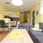Wohn- und Essbereich mit Küchenzeile, Sofa und Stufen zur oberen Etage.