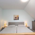Schlafzimmer mit Doppelbett, Nachttischen und Schrank unter schräger Decke.