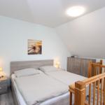 Schlafzimmer mit Doppelbett, Nachttischen und Kleiderschrank unter schrägem Dach.
